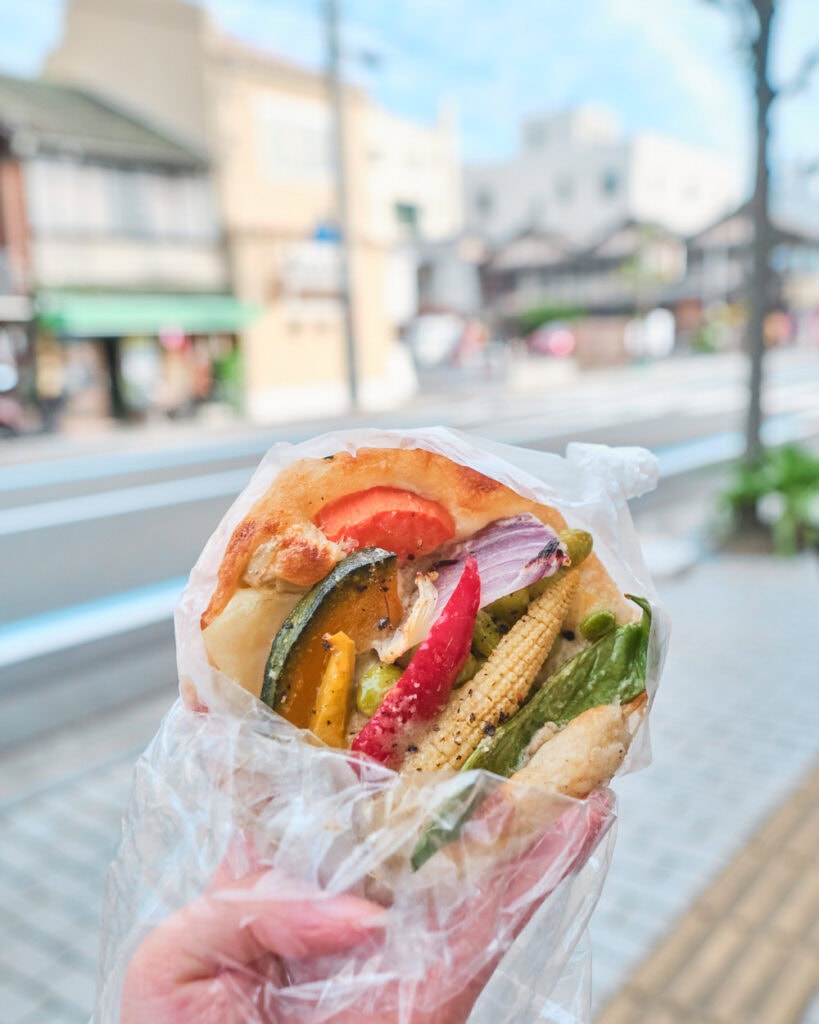 Korobakey pastry topped with seasonal veggies, including baby corn, edamame, kabocha squash, carrot, and red onion on the streets of Onomichi