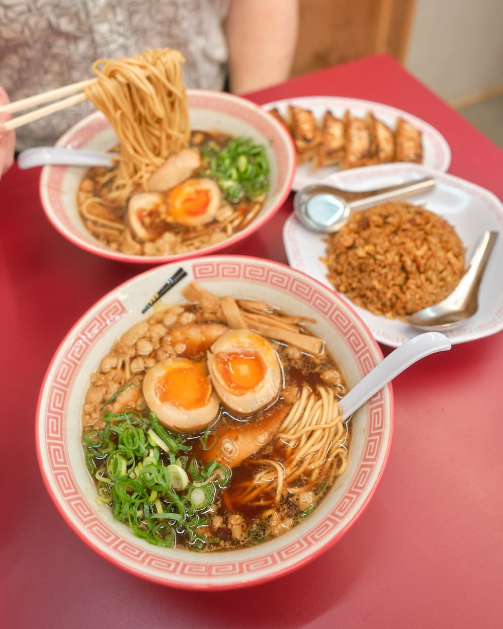 Bowl of Onomichi Ramen with ajitamago, pork chaser, green onions, bamboo shoots. Also a side of gyoza dumplings and fried rice.