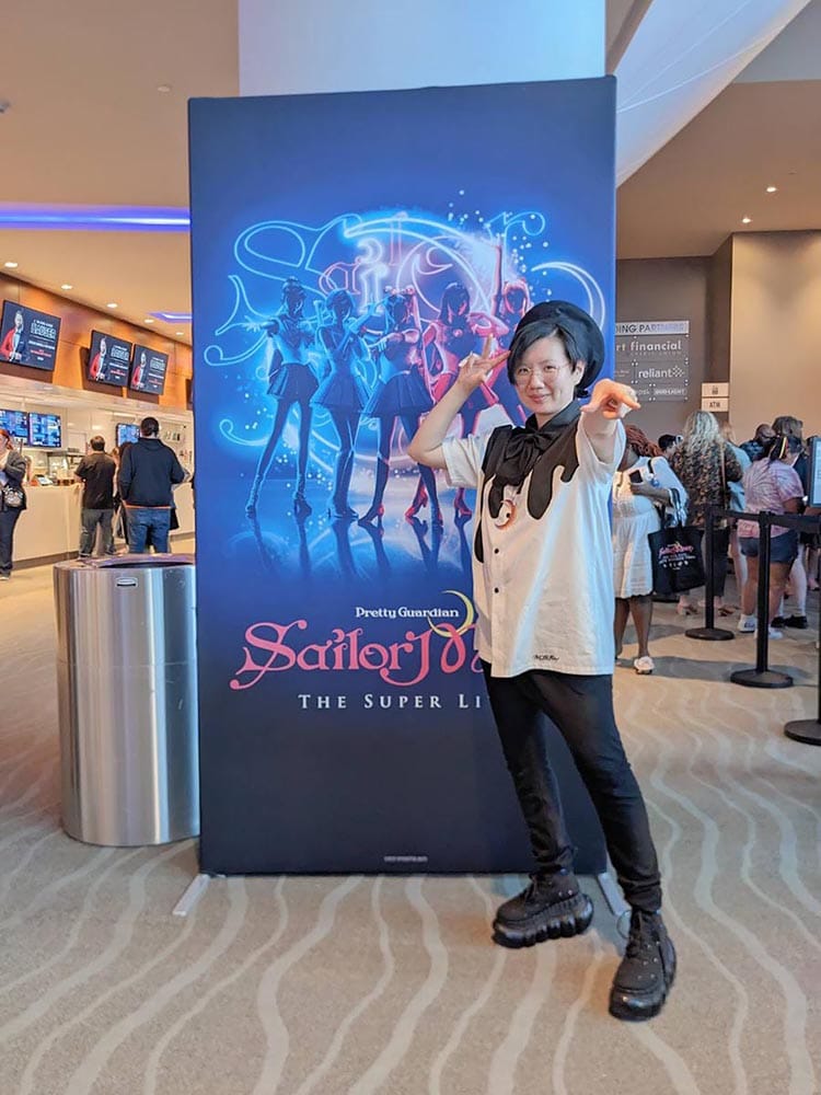 Stephano posing like Sailormoon in front Sailor Moon the Super Live in Houston backdrop