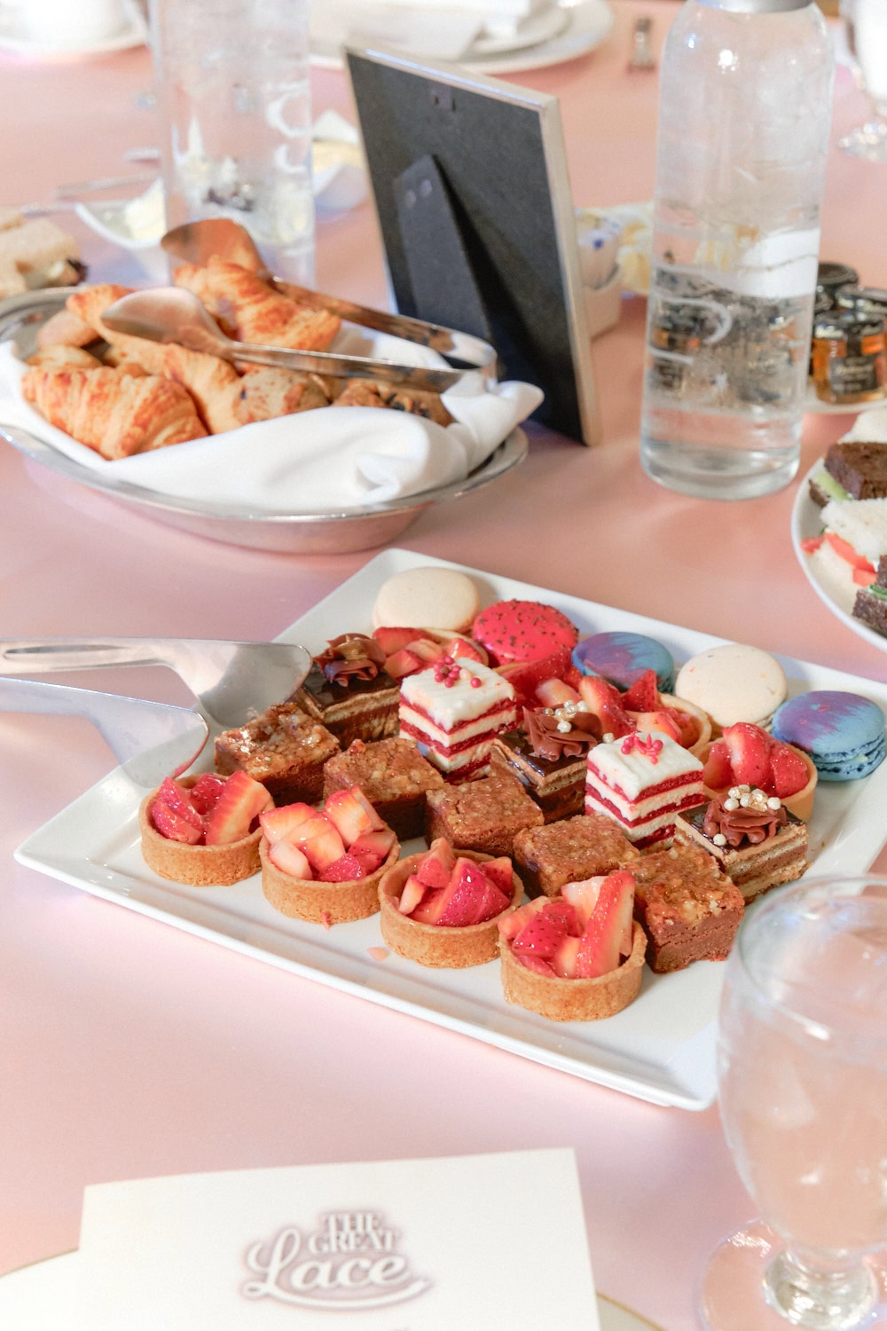 Plates of assorted mini desserts, croissants, and finger sandwiches.