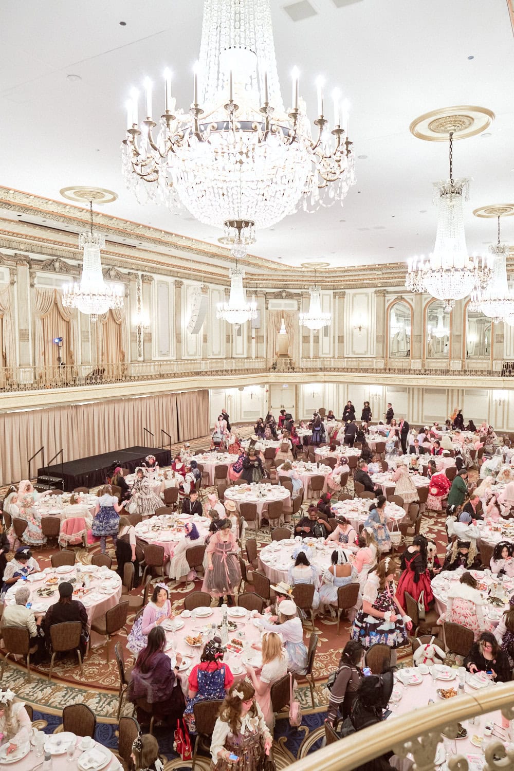 Overhead view of full tables with attendees from second floor with chandeliers on roof.