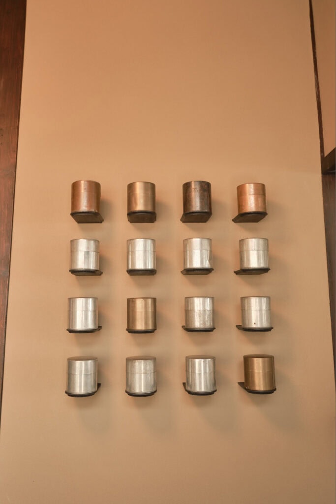Metal tea canisters in a 4 by 4 row mounted to a wall