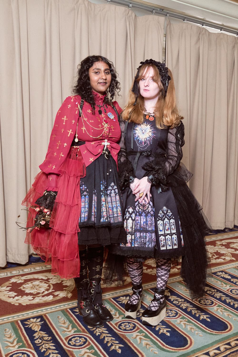 Two gothic lolitas wearing matching stained glass printed dresses.