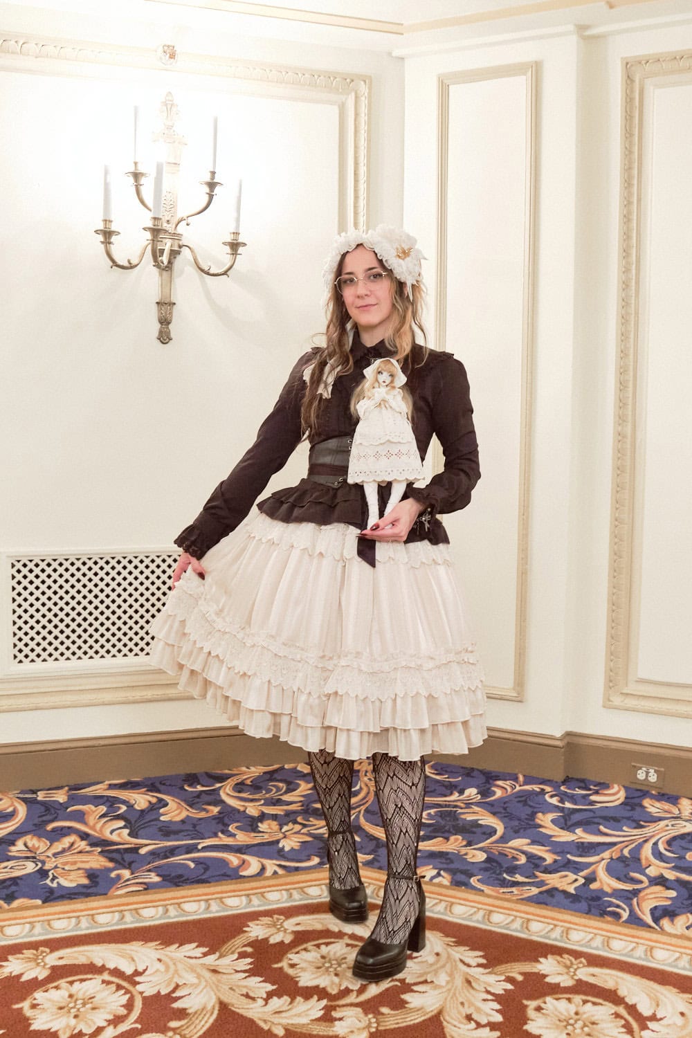 Classic lolita wearing black and cream. She is holding a small doll in hand.