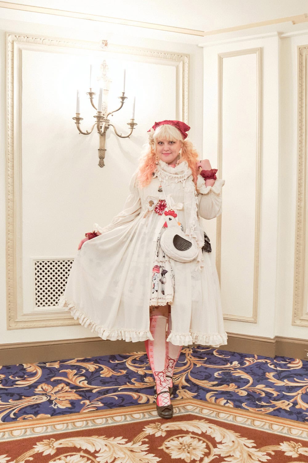 Classic lolita wearing white peignoir over mushroom themed dress, red headdress, and chicken shaped bag.