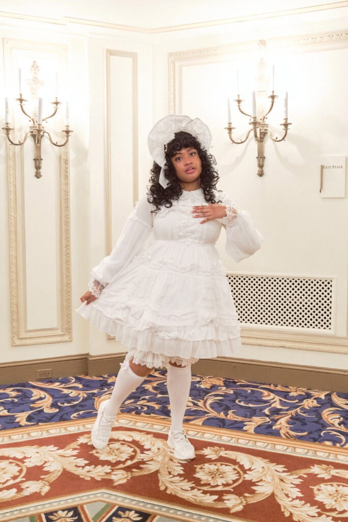 Sweet lolita wearing solid all white outfit with bonnet, blouse, bloomers, and knee high socks.