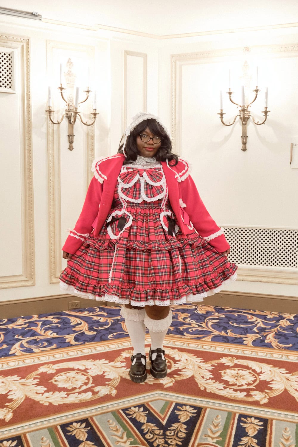 Sweet lolita wearing red jacket on top of plaid dress with heart accents.