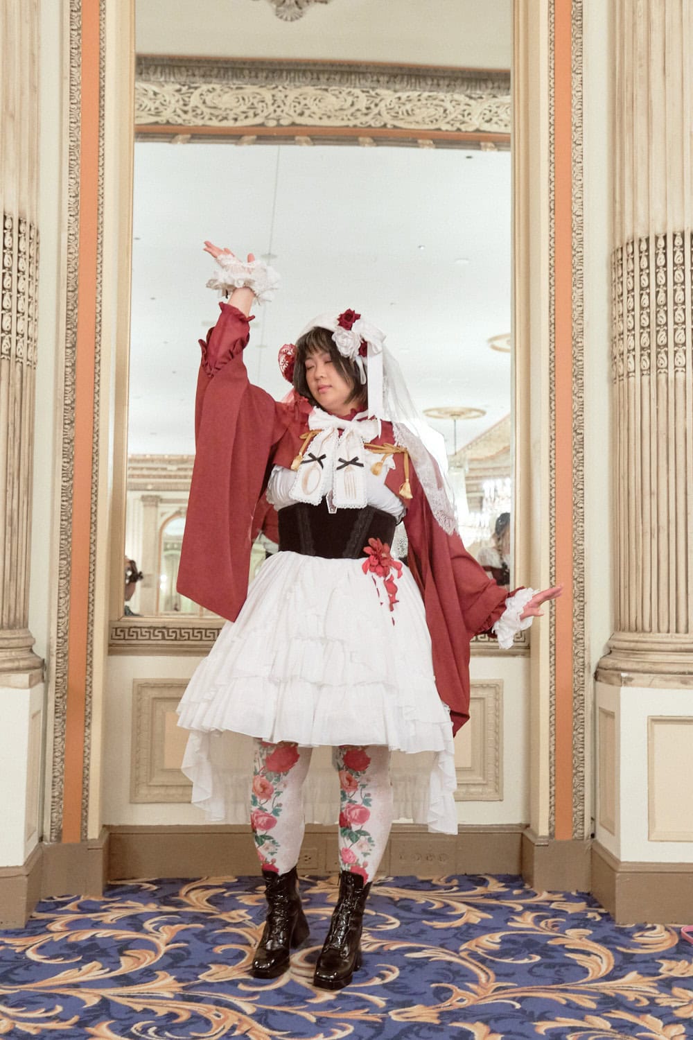Classic lolita wearing white dress with red kimono sleeve bolero and rose accessories.