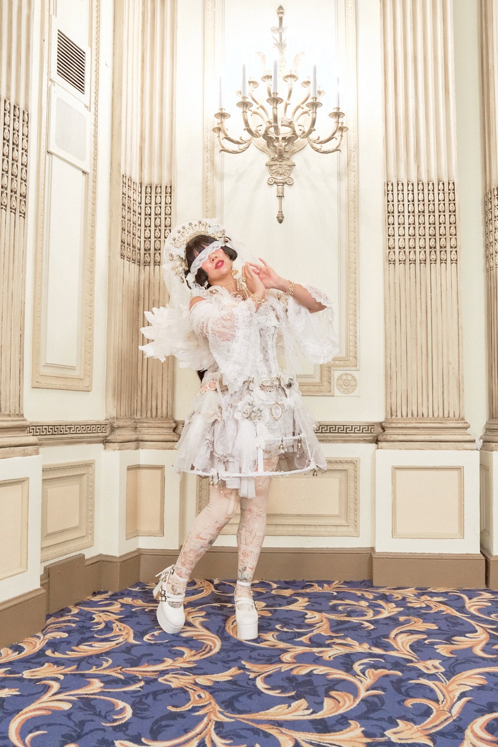 Lolita wearing angel themed white outfit featuring multiple intricate gold accessories.