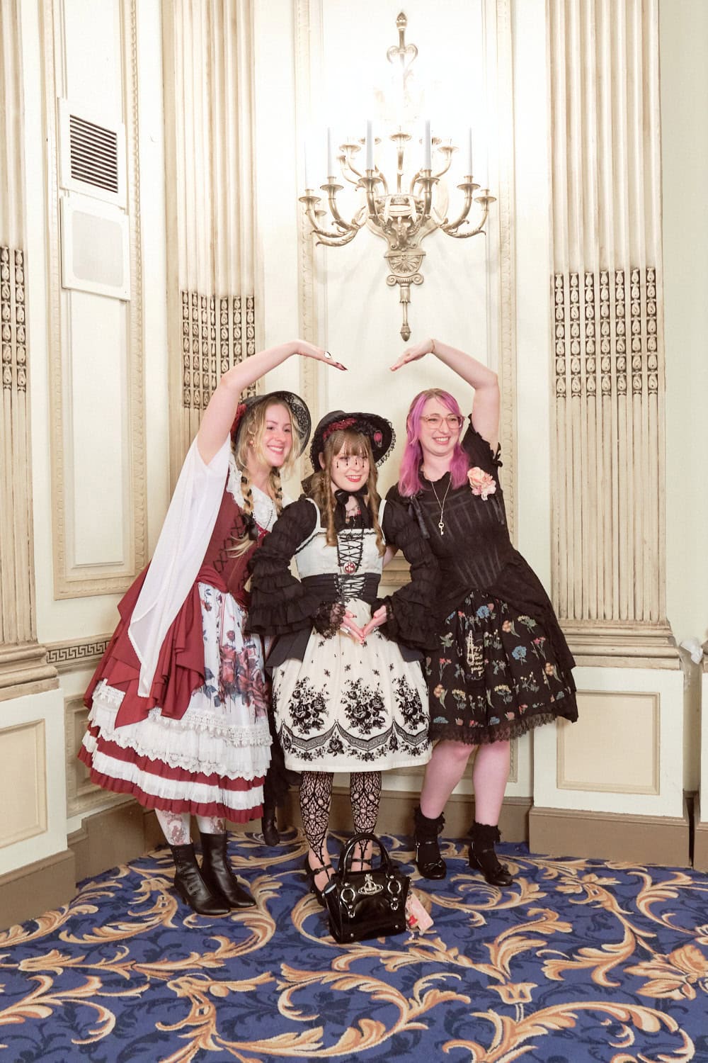 Group of three lolitas linking arms. The outer two made a heart with their arms,