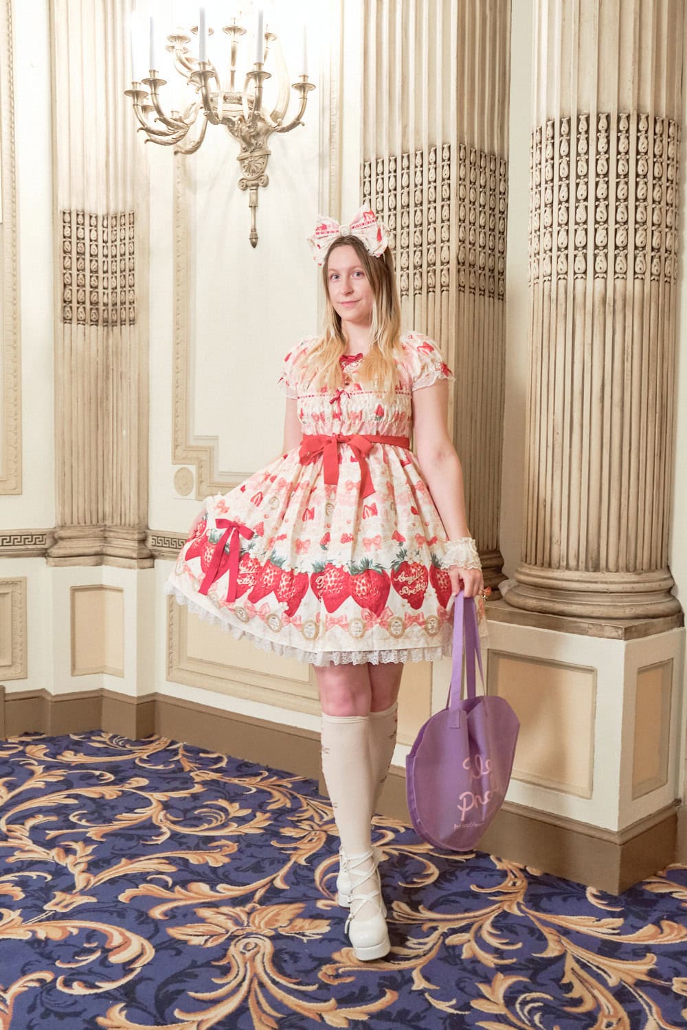 Sweet lolita wearing yellow dress with bold strawberry border print by Angelic Pretty.