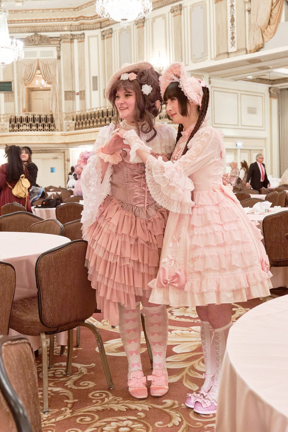 Two lolitas making hand heart together. They are both wearing pink.