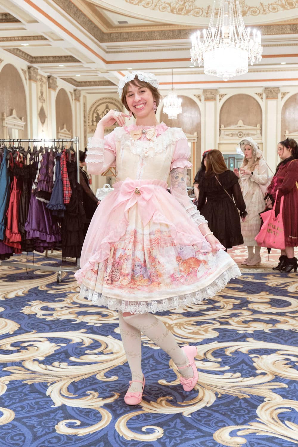 Sweet lolita wearing white dress with pink blouse and pink sheer overskirt.