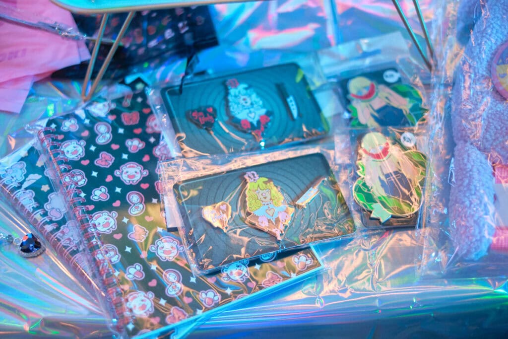 Enamel pins and notebooks as raffle prizes on table.