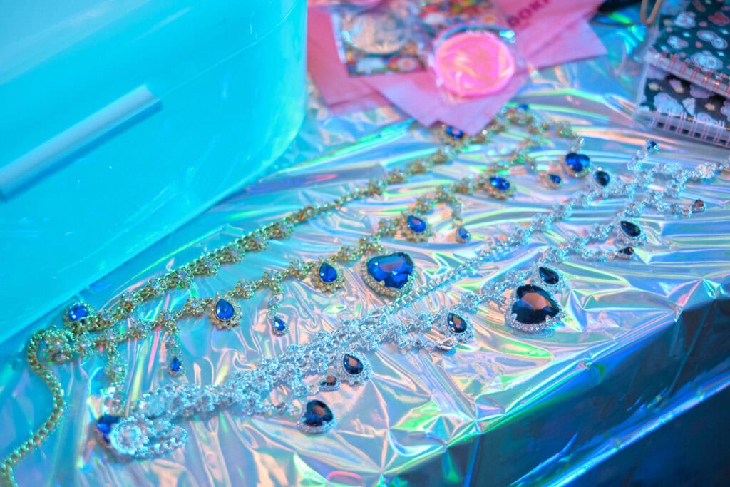 Two jeweled belts with heart charms on table.