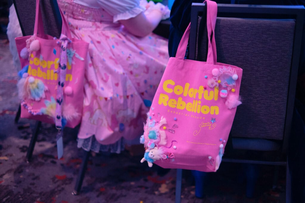 Two pink tote bags hanging on chairs. The tote bags say "Colorful Rebellion".