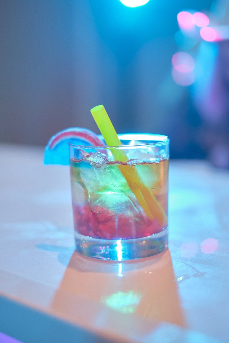 Colorful mocktail with yellow straw on table.