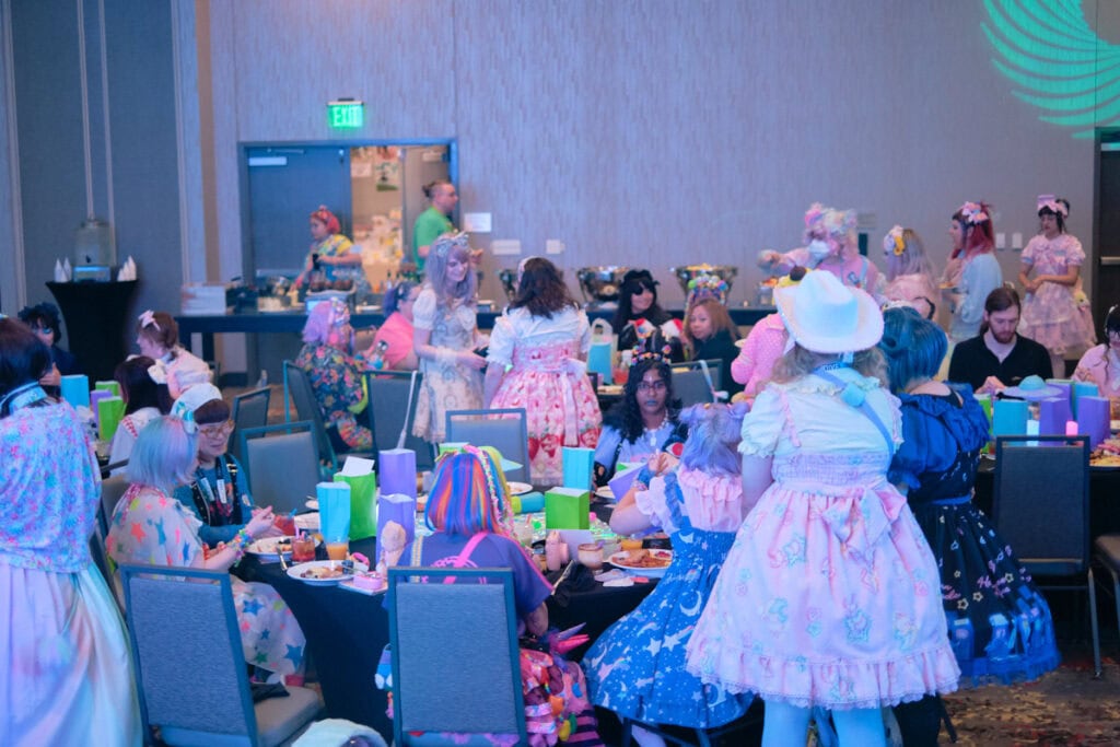 Multiple party tables with attendees sitting and standing.