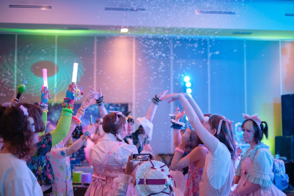 Attendees in circle dancing with soap bubbles in air.