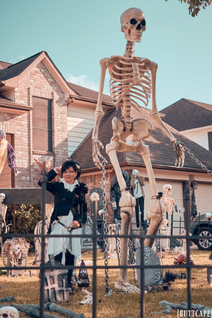 Stephano standing in a yard of Halloween graveyard decorations including a 12 ft skeleton.