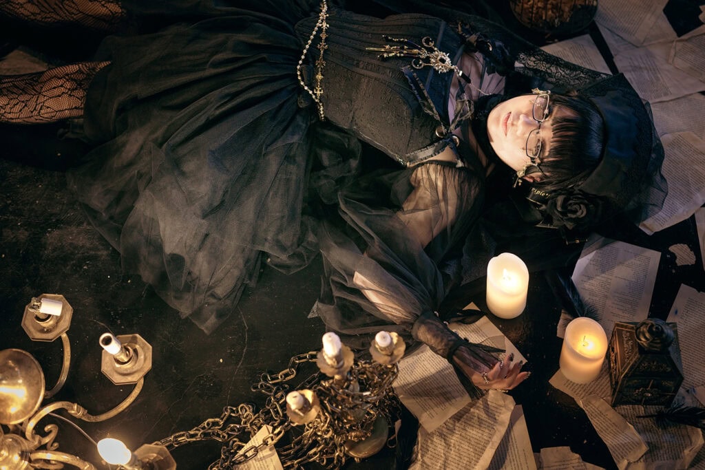 Stephano laying on the floor surrounded by loose book pages and chandeliers.