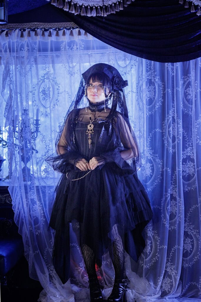 Full body shot standing in front of lace curtain.