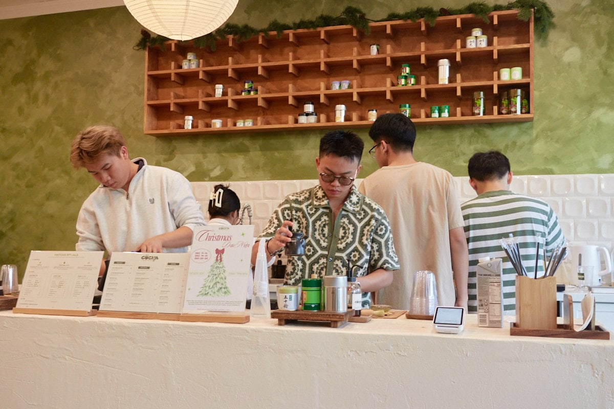 cocha matcha bar, with green walls with white counter and back splash, workers wearing whites and greens