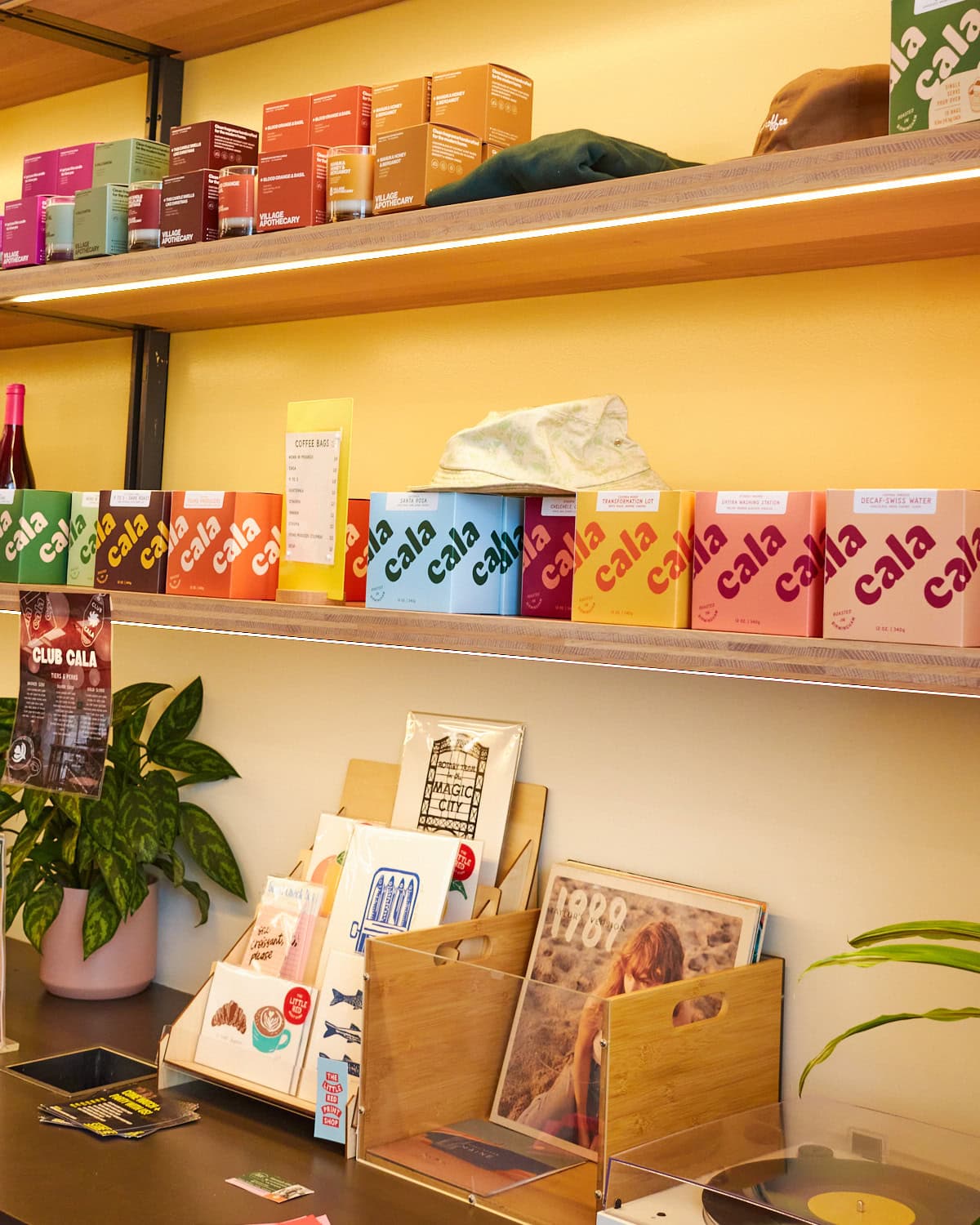 cala coffee merchandise shelf with cala coffee beans in colorful boxes, postcards, and Taylor swift record on display