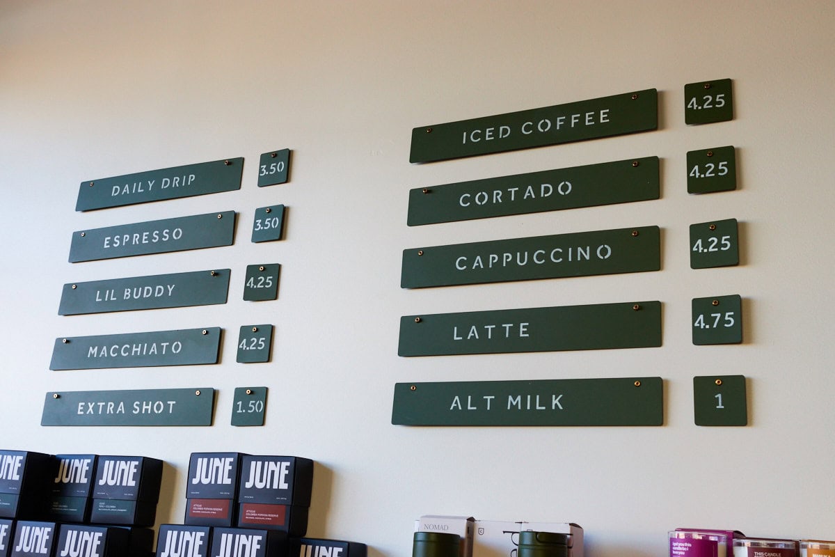 June hanging coffee menu with daily drip, espresso, lil buddy, macchiato, extra shot, iced coffee, cortado, cappuccino, latte, and alt milk pricing