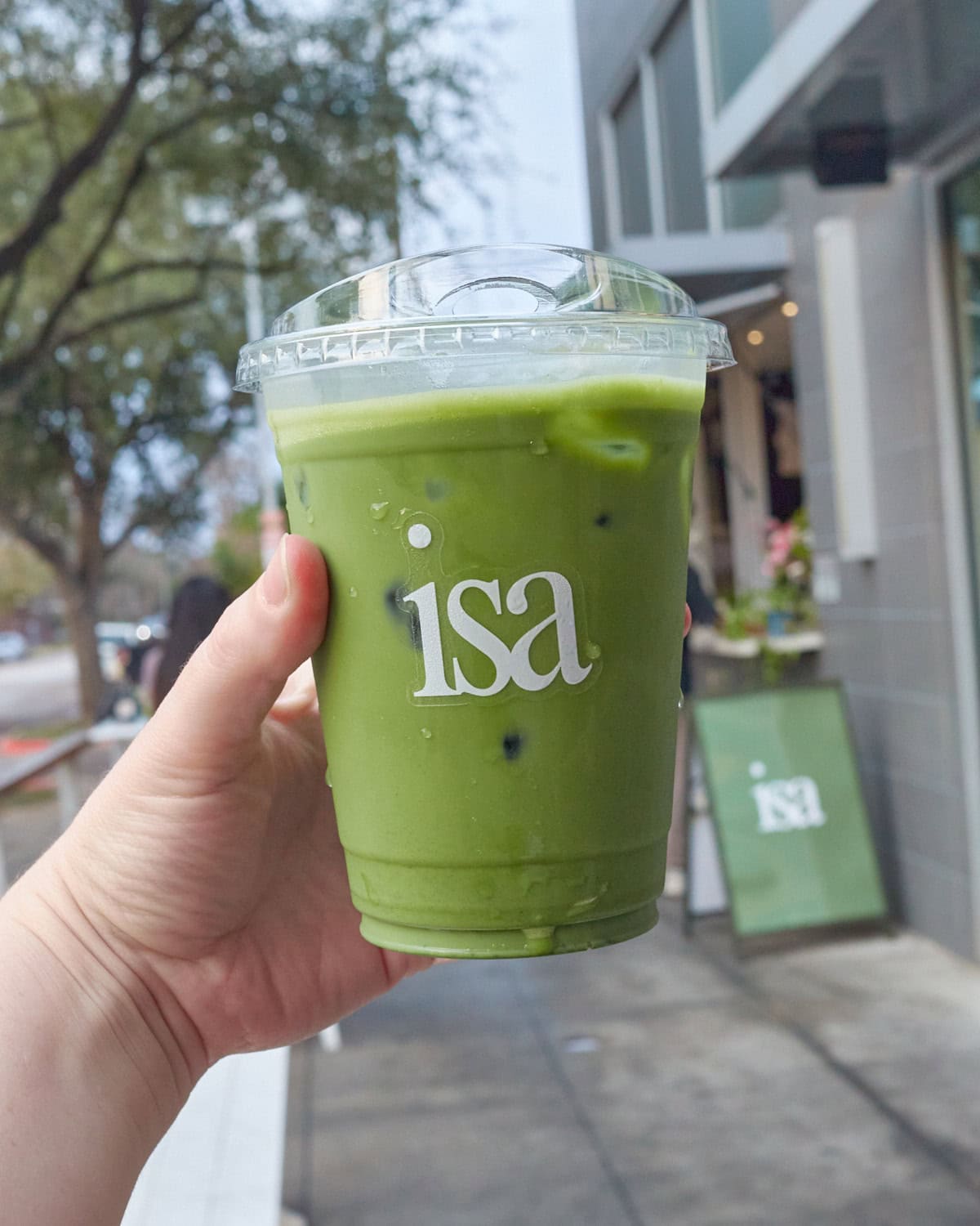 isa matcha latte being held in front of isa walk up window