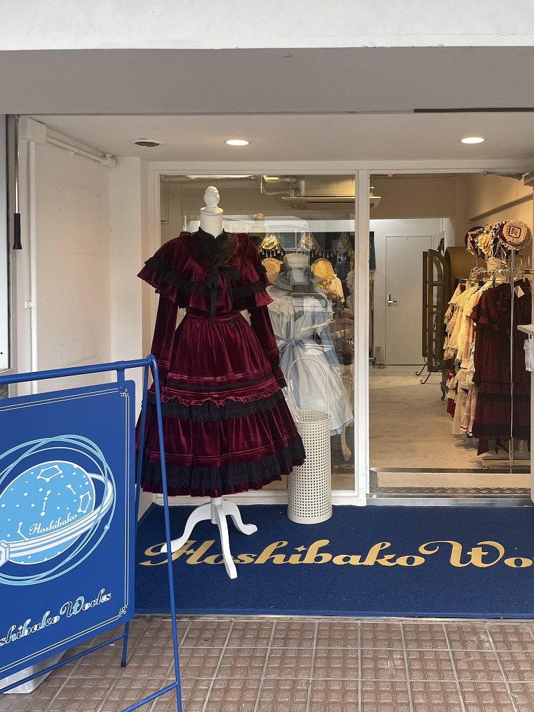 Hoshibako Works store front. The mannequin outside the shop wears a red velvet cape and long sleeve lolita dress.