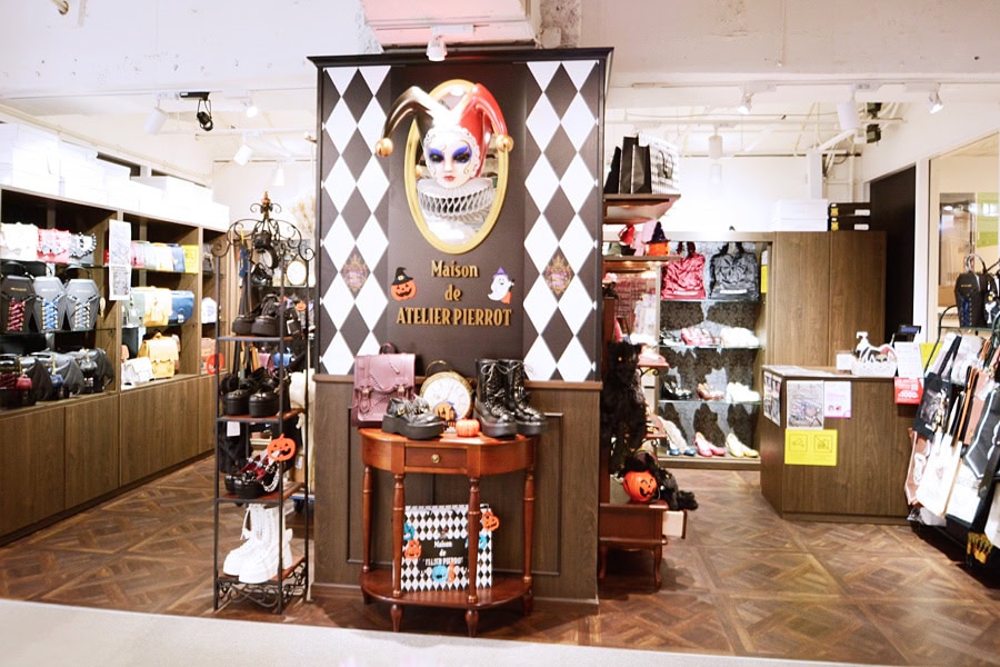 Maison de Atelier Pierrot store front inside of LaForet department store. The shop sells purses and shoes. The center column has a wall sculpture of a pierrot's head.