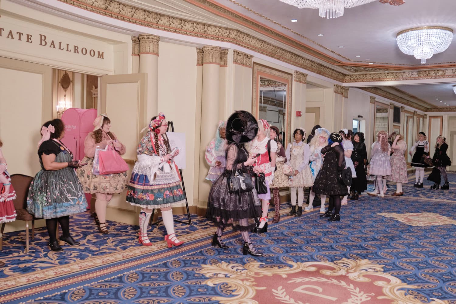 Hallway shot of lolitas waiting to enter the state ballrooom to go shopping. There are 3 lolitas exiting the room.