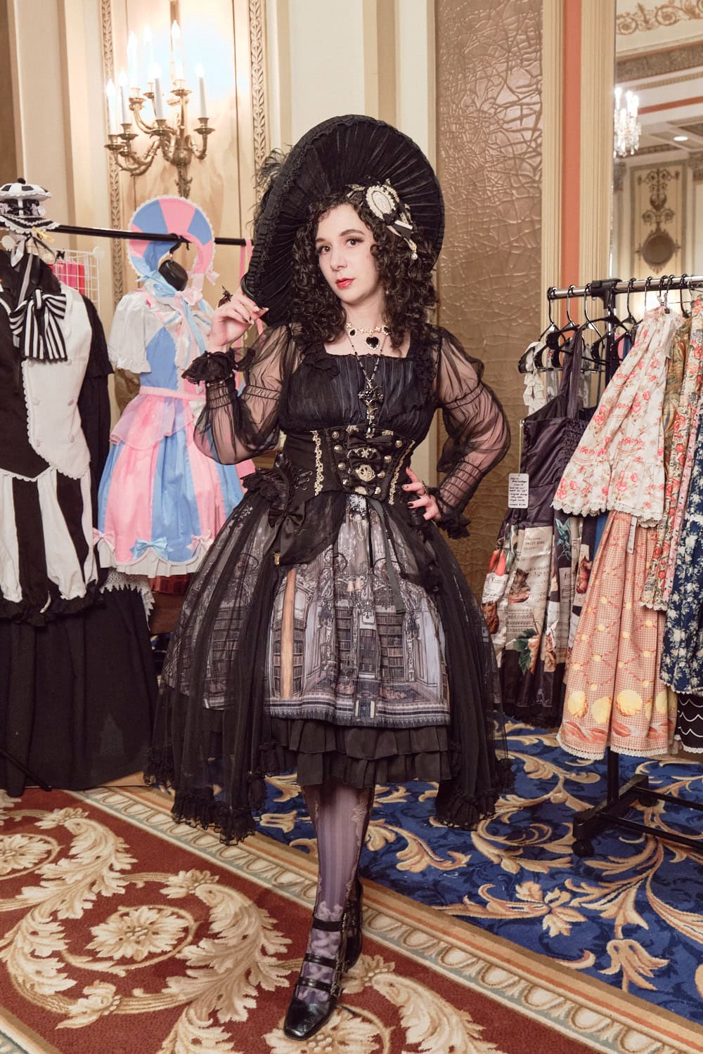 Attendee wearing classic lolita with large dramatic dress hat and architectural print dress with tulle overlay.
