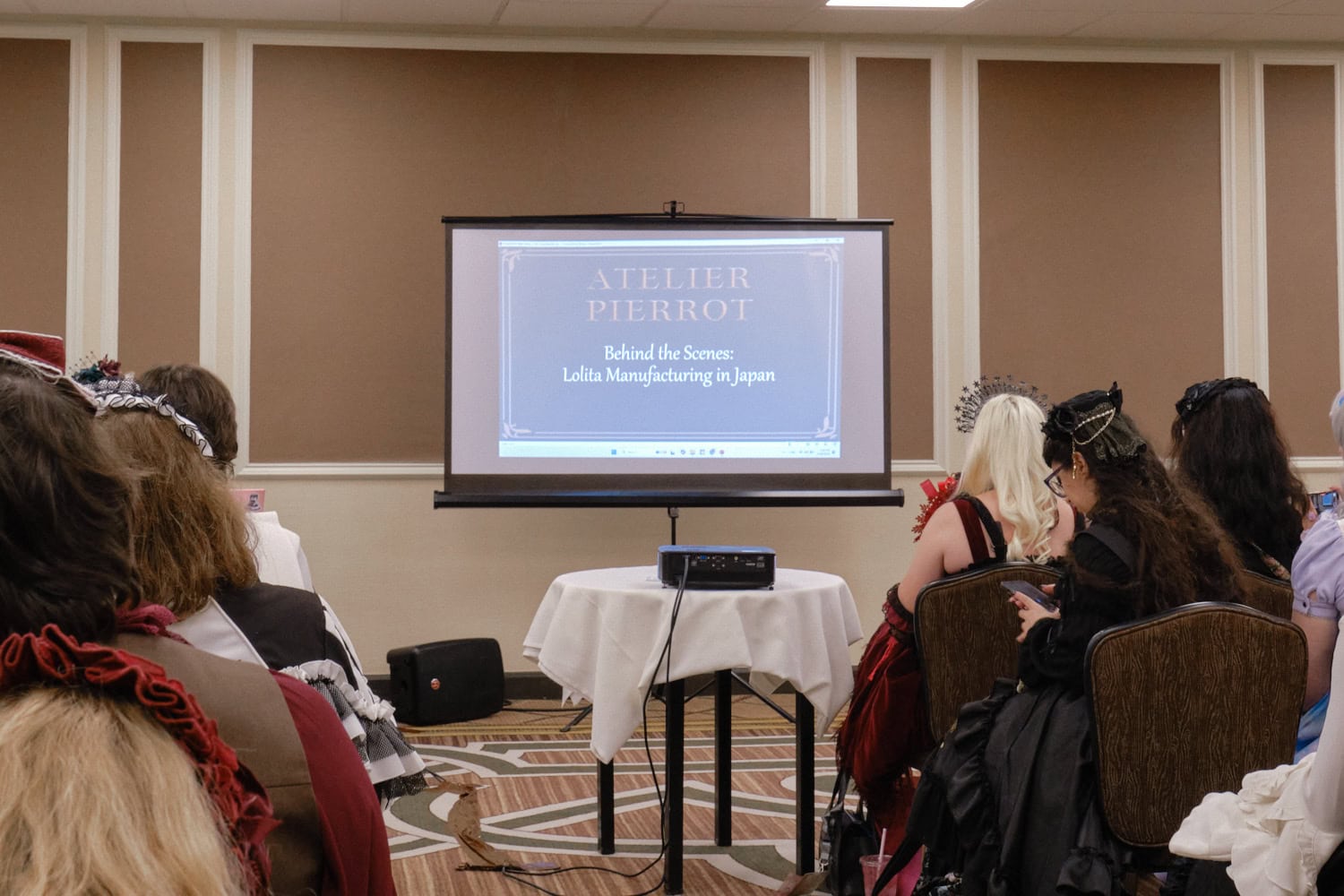 Projector screen with the title slide "Atelier Pierrot. Behind the Scenes: Lolita Manufacturing in Japan."