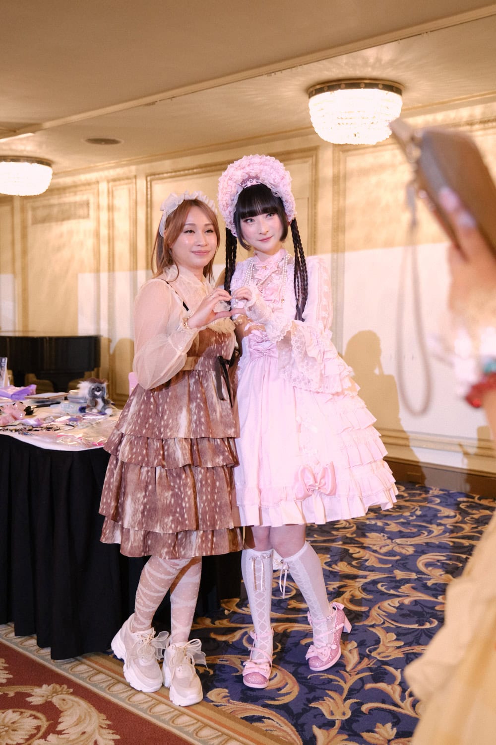 Attendee posing with RinRin Doll for photo to be taken on their cell phone.