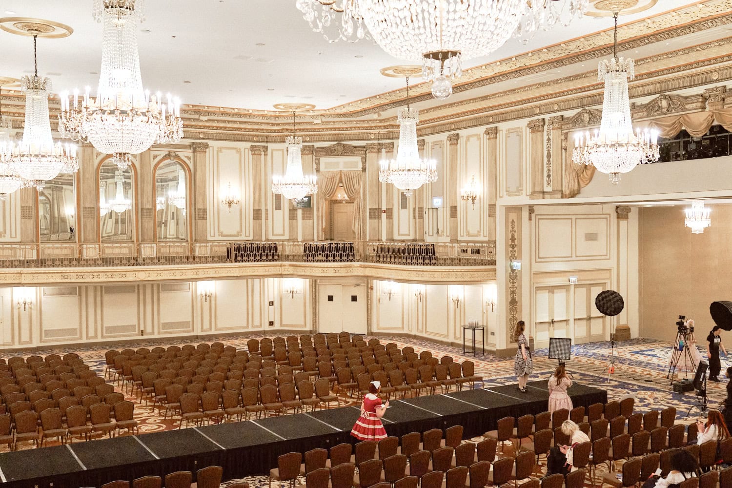 The fashion show room during rehearsal. A model practiced their walk onstage. The seats are empty.