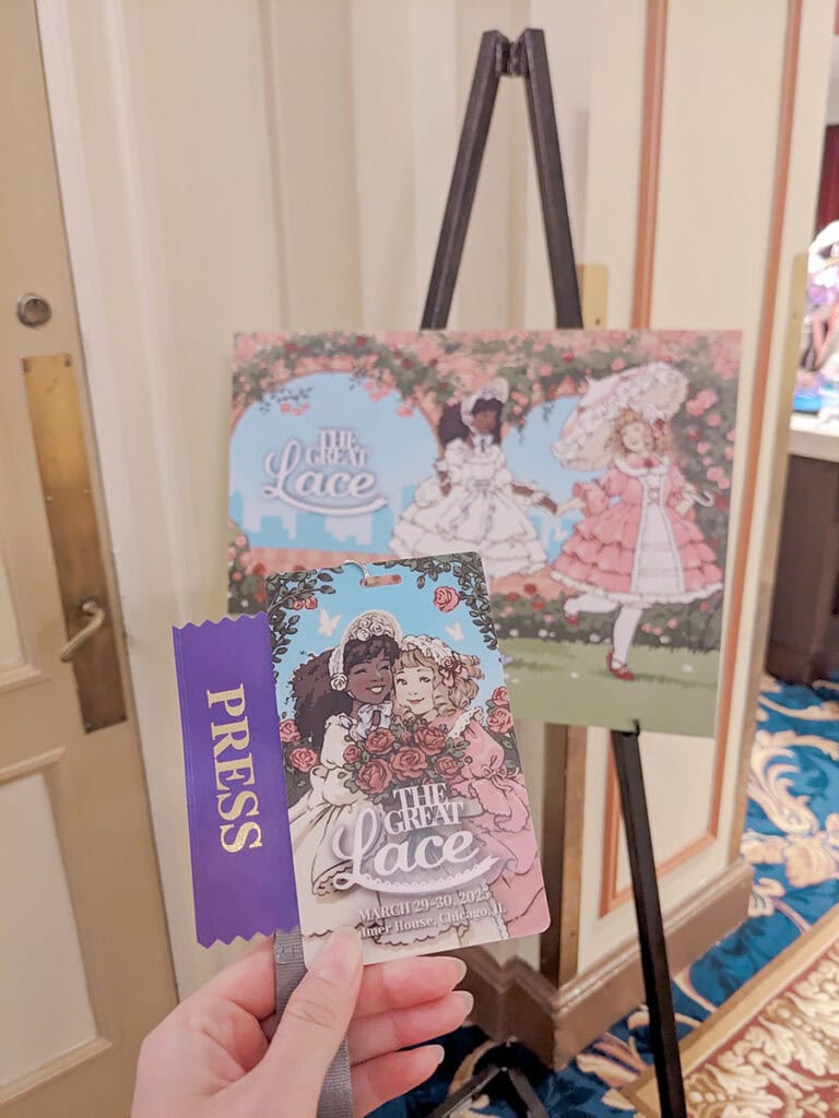 Holding press badge in front of promo art sign.