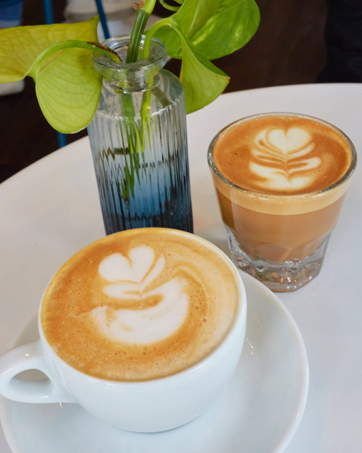 Latte in a white cup and glass cup with a cortado 