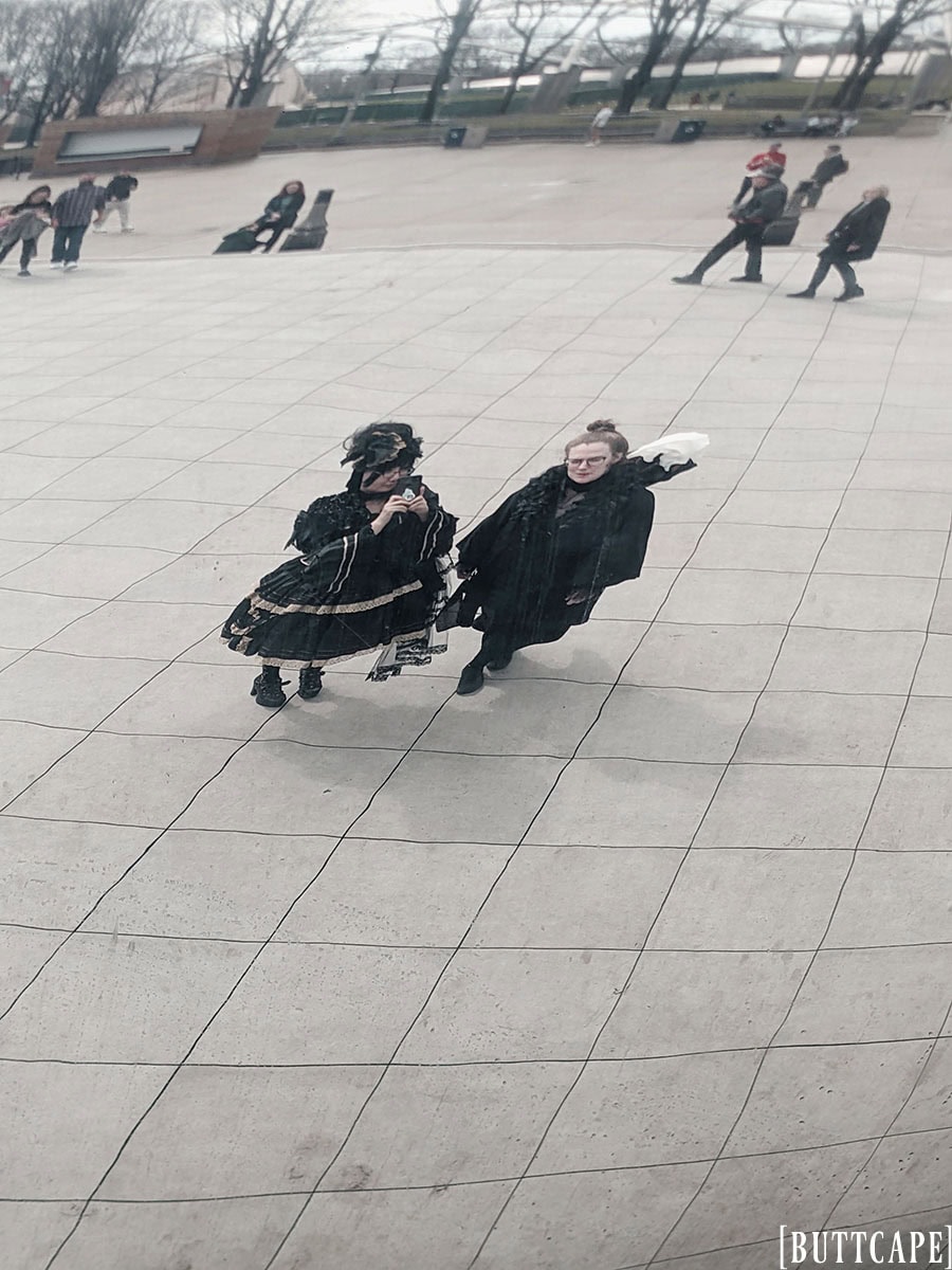 Stephano and Sarah looking into the reflective surface of Cloud Gate. Stephano takes a photo on her phone.